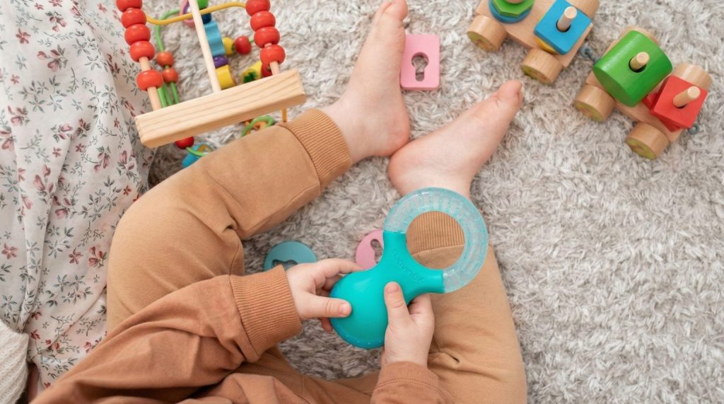 Bebé sujeta un mordedor frío con la mano.